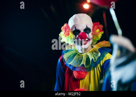 Bild der Clown mit roten Ballon in der Nacht auf der Straße Stockfoto