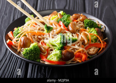 Rühren braten Soba mit Shiitake Pilze, Brokkoli, Möhren, Paprika close-up auf einem Teller auf den Tisch. Horizontale Stockfoto