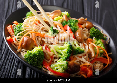 Japanische Soba-Nudeln mit Shiitake Pilze, Brokkoli, Möhren, Paprika close-up auf einem Teller auf den Tisch. Horizontale Stockfoto