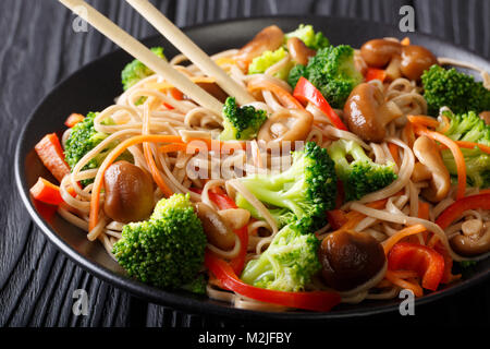 Japanisches Essen: Soba Nudeln mit Champignons, Brokkoli, Möhren, Paprika close-up auf einem Teller auf den Tisch. Horizontale Stockfoto