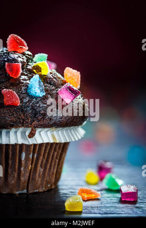 Nahaufnahme von Schokolade Muffin mit Bonbons auf Holztisch mit bokeh Hintergrund. Selektive konzentrieren. Stockfoto