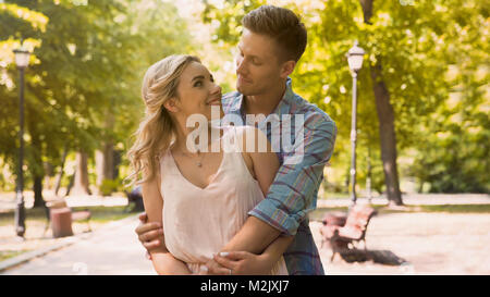 Netter Kerl und Mädchen an einander mit Liebe zärtlich kuscheln in Park, Filmmaterial Stockfoto