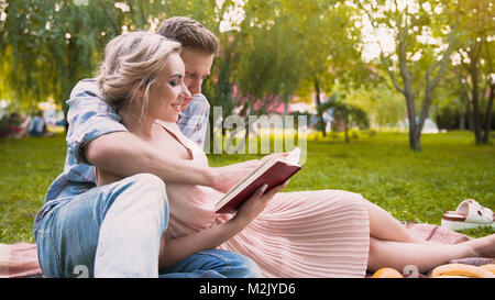 Caring Guy lesen Geschichte zu seiner schönen Frau, sanft Ihre, Datum in Park umarmen Stockfoto