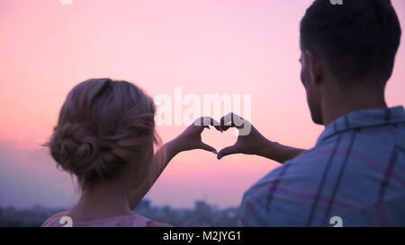 Liebhaber, die ihre Hände zusammen in der Form von Herzen, zeigen ihre Liebe Stockfoto