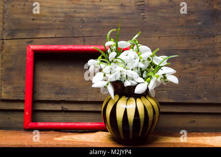 Snowdrop Blumen in einer Vase gegen rustikalen Holzmöbeln Hintergrund Stockfoto