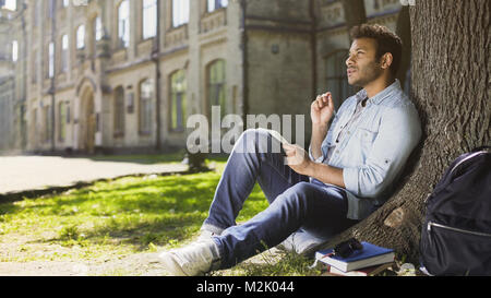 Studenten sitzen mit Notebook unter Baum tun Home Zuordnung, Studium Stockfoto