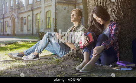 Männliche und Weibliche Fremde sitzen unter Baum, erste Sitzung, Unentschlossenheit Stockfoto