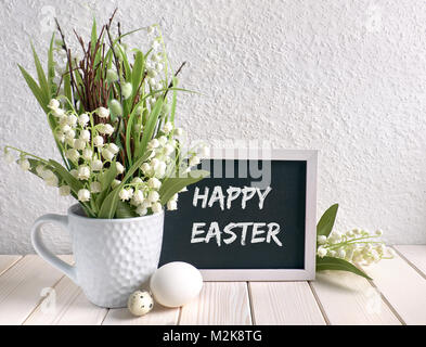 Ostern Zusammensetzung mit Blackboard mit Keramik Henne, Eier dekoriert und und Maiglöckchen Blumen, Bildunterschrift "Frohe Ostern" Stockfoto