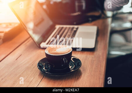 Latte Kaffee mit Laptop arbeiten im Cafe Konzept vintage Farbe Ton Stockfoto