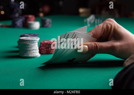 Poker Tisch während eines Spiels. Vier Asse Karten in der Hand halten. Chips und Karten auf den Tisch. Stockfoto