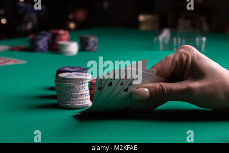 Poker Tisch während eines Spiels. Vier Asse Karten in der Hand halten. Chips und Karten auf den Tisch. Stockfoto