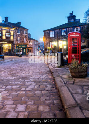 Leuchtet auf entlang der gepflasterten Hauptstraße in Haworth Dorf in der Dämmerung West Yorkshire England Stockfoto