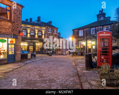 Leuchtet auf entlang der gepflasterten Hauptstraße in Haworth Dorf in der Dämmerung West Yorkshire England Stockfoto