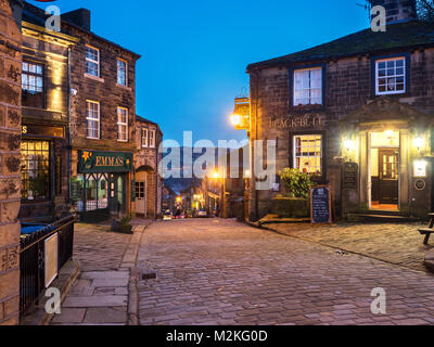 Leuchtet auf entlang der gepflasterten Hauptstraße in Haworth Dorf in der Dämmerung West Yorkshire England Stockfoto