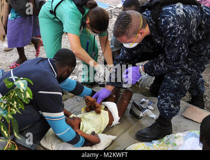 100119-N-6247V-624 CARREFOUR, Haiti (19. Januar 2010) Lt. Kristina Rogish, Fliegerarzt zugewiesen, Carrier Air Wing (CVW) 17 behandelt ein verletztes Kind, während Hospital Corpsman 1. Klasse Adam Kishman lenkt ihre Aufmerksamkeit auf ein Stofftier in der Killick haitianische Küstenwache Klinik in Carrefour, Haiti. Personal aus dem Flugzeugträger USS Carl Vinson (CVN-70) und CVW-17 führen humanitäre und Katastrophenhilfe Soforthilfe in der Klinik als Teil der Operation Unified Antwort, nachdem eine Erdbeben der Stärke 7,0 in Haiti am 12. Januar 2010 schwere Schäden verursacht. (U.S. Navy Photo von Masse Commun Stockfoto