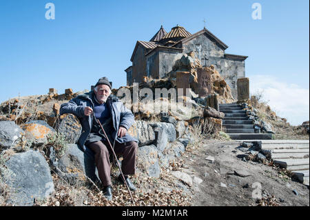 Alte Mann sitzt in der Nähe des Komplex von Sevanavank besteht aus Sts. Kirchen Arakelots und Karapet. Stockfoto