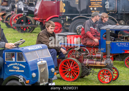 Junge Männer fahren in Miniatur Traktor Dampfmaschinen, Masham, North Yorkshire, Großbritannien Stockfoto