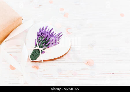 Happy Mother's Day Grußkarte. cookie Herz mit Lavendel Bouquet und Handwerk Geschenkbox auf weißen Holzmöbeln im Landhausstil Hintergrund mit Konfetti. Platz für Tex Stockfoto
