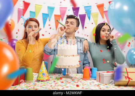 Jugendliche mit Party Hörner und einen Kuchen zum Geburtstag feiern. Stockfoto