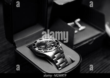 Der klassische Design des neuen eleganten teuren Edelstahl Silber Chrom Männer Uhren in einem Feld in der Nähe von manschettenknöpfe Accessoires Stockfoto