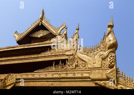 Dekorationen von einem reich verzierten und goldfarbenen Dach eines Gebäudes an der königlichen Mandalay Palace in Mandalay, Myanmar (Burma) an einem sonnigen Tag. Stockfoto