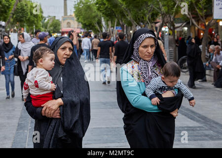 Teheran, Iran - 27. April 2017: zwei iranische Frauen in hijabs mit Kindern in ihre Arme sind zu Fuß entlang der Straße von Shahre Rey. Stockfoto