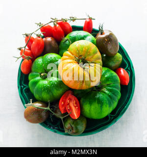 Verschiedene Arten von Tomaten auf einem Schild auf einem weißen Tisch aus Stein. frische reife Zutaten für eine gesunde Ernährung die richtige Ernährung. Stockfoto
