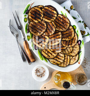 Gegrillte Auberginen gewürzt mit Olivenöl auf einem weißen Tisch aus Stein Stockfoto