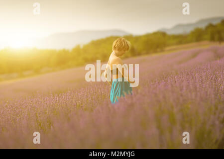 Junge Frau trägt blaue Kleid in einem Lavendelfeld posieren. Konzept positive Stimmung. Weichzeichner Effekt und bokeh Unschärfe-Effekten im Hintergrund. Stockfoto