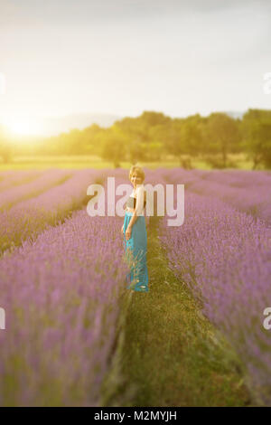 Junge Frau trägt blaue Kleid in einem Lavendelfeld posieren. Konzept positive Stimmung. Weichzeichner Effekt und bokeh Unschärfe-Effekten im Hintergrund. Stockfoto