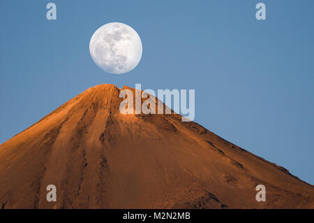 Der Vollmond über dem Gipfel des Mount Teide vor blauem Himmel bei Sonnenuntergang, Teneriffa, Kanarische Inseln Stockfoto