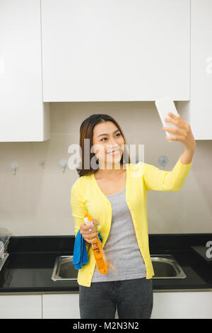 Schöne asiatische Frau tut selfie mit einem Smartphone und lächelnd während der Reinigung Küche Stockfoto