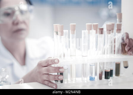 Nahaufnahme Blick auf weibliche Forscher unter Reagenzglas mit Flüssigkeit Stockfoto