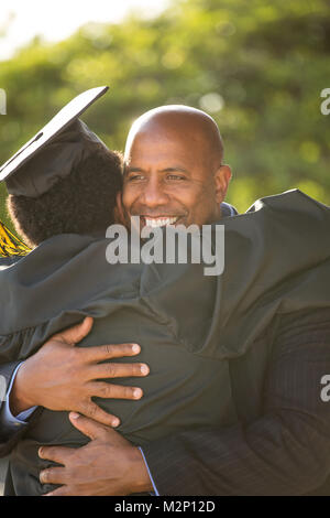 Vater umarmt seinen Sohn zu seinem Abschluss. Stockfoto