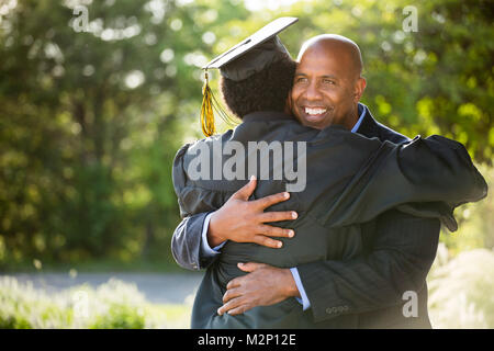 Vater umarmt seinen Sohn zu seinem Abschluss. Stockfoto