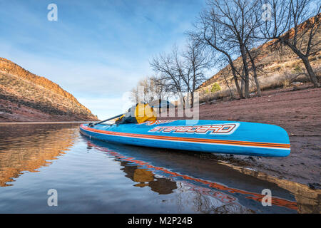 FORT COLLINS CO, USA - Januar 22, 2017: Winter Stand Up Paddling - All Star Racing paddleboard von Steuerbord auf einem Ufer der Horsetooth Behälter. Stockfoto