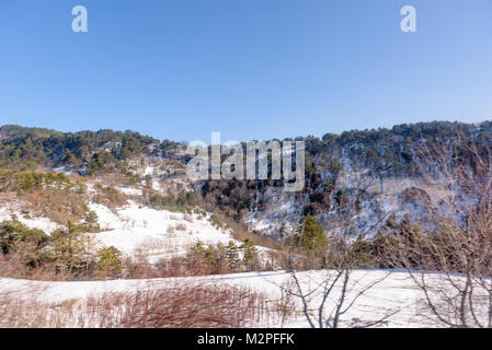 Wunderschöne Landschaft Bergblick von kalten Landschaft mit Wäldern und schneebedeckten Bergrücken mit blauem Himmel Stockfoto