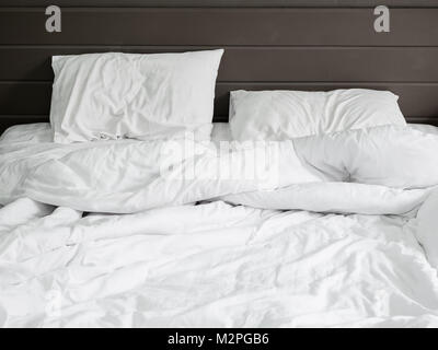 Weiße Bettwäsche Bettwäsche und Kissen auf natursteinmauer Raumhintergrund, Ungemacht unordentliche Bett nach Komfort schlafen Konzept Stockfoto
