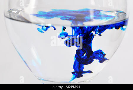 Wein Glas mit Wasser und blauen Tropfen Farbstoff gefüllt Stockfoto