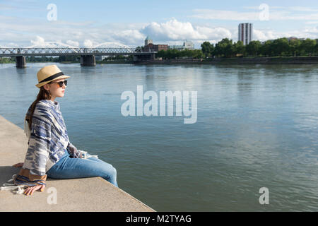 Junge Frau sitzt in der Hafenpromenade von Mannheim, Baden-Württemberg, Deutschland Stockfoto