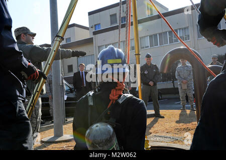 YOKOTA AIR BASE, Japan - Col. Bill Ritter, 374 Airlift Wing stellvertretender Kommandeur und Mitglieder der Führung beobachten, wie Kenji Ohkoshi, ein Feuerwehrmann mit dem 374 Bauingenieur Squadron, in ein Mannloch während eines begrenzten Raum Rescue Team Demonstration abgesenkt wird. Die Demonstration gab Führung die Möglichkeit, die Fähigkeit der Mannschaft zu beobachten Rettungsaktionen in explosionsgefährdeten Umgebungen durchzuführen, beschränkt. (U.S. Air Force Foto/Capt. Raymond Geoffroy) Kenji Ohkoshi, ein Feuerwehrmann Demonstration von # FIRMA PACOM Stockfoto