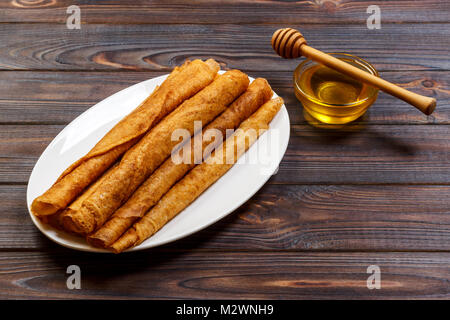 Stapel von leckeren Pfannkuchen mit Honig im Glas auf Holz- bachground. Stockfoto