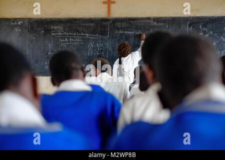 Kibuye/Ruanda - 08/26/2016: Lehrer und Schüler in Mathematik Unterricht in einem Klassenraum in einer Schule in Afrika. Eine Tafel und Kreuz können im b gesehen werden. Stockfoto