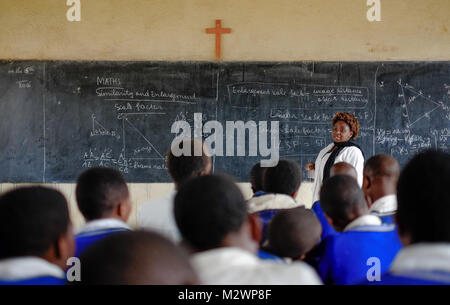 Kibuye/Ruanda - 08/26/2016: Lehrer und Schüler in Mathematik Unterricht in einem Klassenraum in einer Schule in Afrika. Eine Tafel und Kreuz können im b gesehen werden. Stockfoto