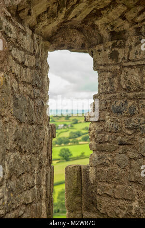 Blick durch das Loch in der Wand der mittelalterlichen Burg auf die umliegende Landschaft in Wales Stockfoto