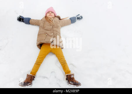 Foto von Mädchen liegt auf dem Rücken im Schnee im Park Stockfoto