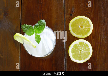 Glas Limonade und Hälften von Zitronen auf hölzernen Tisch Stockfoto