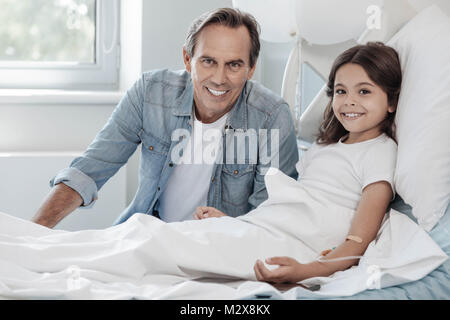 Liebevoller Vater sitzt neben seine bezaubernde Tochter im Krankenhaus Stockfoto