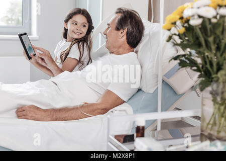 Fröhliche Tochter hatting mit Ihrem positiv gesinnten Vater im Krankenhaus Stockfoto