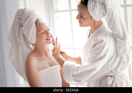 Gerne fröhliche Frau, die ihre Töchter Reinigung Gesicht Stockfoto